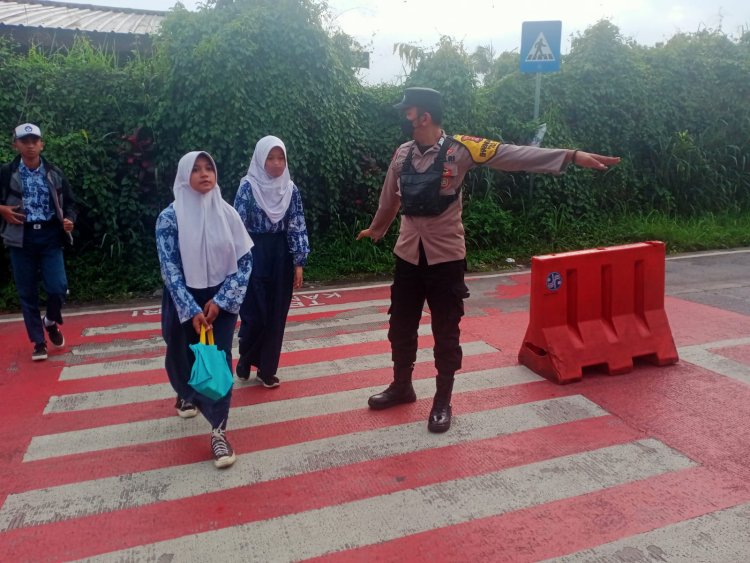 Bhabinkamtibmas Desa Citapen Polsek Ciawi Polres Bogor Bripka M. Obay Wijaya Melaksanakan Gatur Lalin Membantu Menyebrangkan Anak-Anak Sekolah